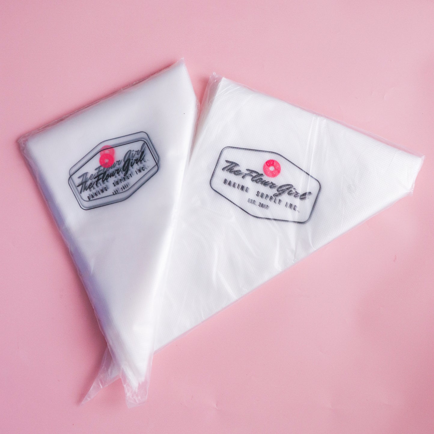 Two white bags with a logo on a pink background